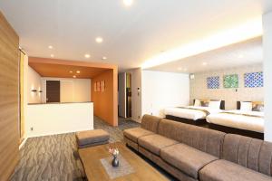 a hotel room with two beds and a couch at HOTEL COCON in Fukuoka