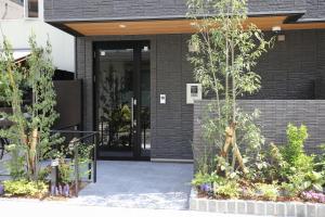 a black brick building with a door and some plants at HOTEL COCON in Fukuoka