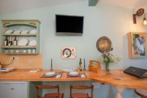 a kitchen with a table and a tv on a wall at Gregos Rooftop Suite City Center w. Sea View in Corfu Town