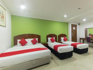 a bedroom with two beds with red and white pillows at OYO 805 Hotel Run Star in Kuala Lumpur