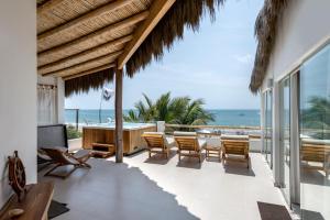 une terrasse avec une table et des chaises et l'océan dans l'établissement Qalma Punta Sal, à Canoas de Punta Sal