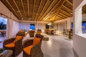 an open living room with chairs and a table at Qalma Punta Sal in Canoas De Punta Sal