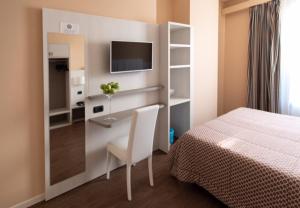 a bedroom with a bed and a desk and a tv at Hotel Enrichetta in Desenzano del Garda