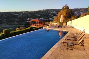 a swimming pool with chairs and a gazebo at Villa HERMIONA in Kouklia