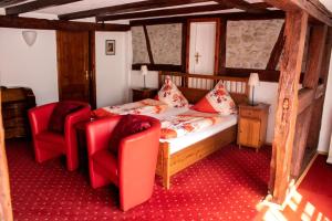 um quarto com uma cama e 2 cadeiras vermelhas em Hotel Herberge zur Traube em Bad Wimpfen