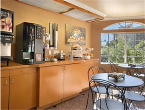 eine Küche mit einem Tisch, Stühlen und einer Mikrowelle in der Unterkunft Super 8 by Wyndham Los Angeles Downtown in Los Angeles