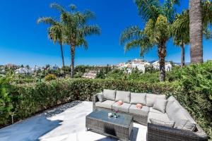eine Couch auf einer Terrasse mit Palmen in der Unterkunft Luxury Townhouse Golden Mile in Marbella