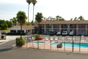 a pool in front of a hotel with palm trees at Colony Inn in Buena Park