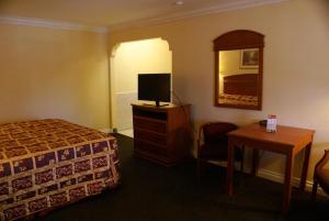 um quarto de hotel com uma cama, uma televisão e uma mesa em Colony Inn em Buena Park