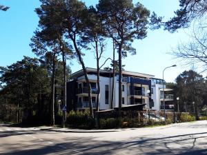 a building on the side of a street with trees at Apartament Fala Bryza in Jurata