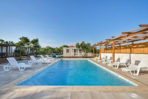 a swimming pool with lounge chairs and a house at Apartments Medanić - Private Pool in Privlaka
