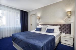 ein Hotelzimmer mit einem großen Bett mit blauer Bettwäsche in der Unterkunft Eurohotel in Lwiw