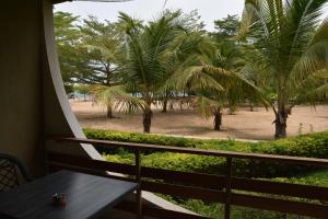 a balcony with a table and palm trees on the beach at Hotel Club du Lac Tanganyika in Bujumbura