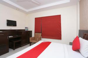 1 dormitorio con cama, escritorio y puerta roja en Hotel Le central, en Haridwar