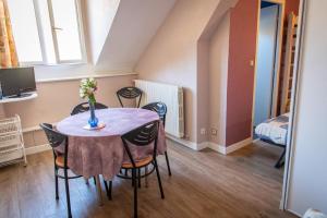 a dining room table with chairs and a vase of flowers on it at Aux Studios du Parc in Plombières-les-Bains