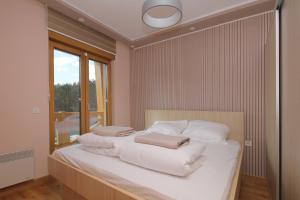 a bedroom with a bed with white sheets and a window at NK11 apartments in Zlatibor