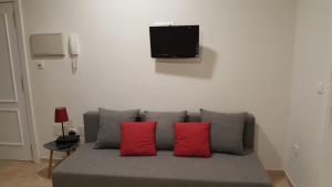 um sofá com duas almofadas vermelhas e uma televisão na parede em Apartamento AGP Centro Histórico em Málaga