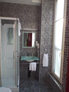 La salle de bains est pourvue d'un lavabo, d'un miroir et d'une douche. dans l'établissement Hôtel Saint Martin, à Orléans