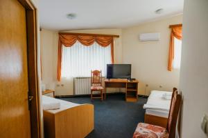 a room with two beds and a desk and a television at Guest House Sv. Nikola in Dugo Selo
