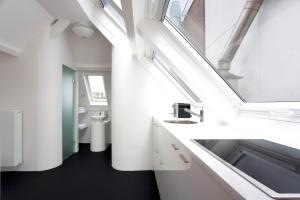 a white bathroom with a sink and a mirror at MAFF Top Apartment in The Hague