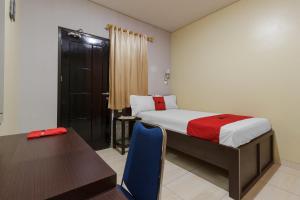 マナドにあるRedDoorz Plus near Pantai Malalayang Manadoのベッドルーム1室(ベッド1台、テーブル、デスク付)