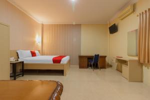 a hotel room with a bed and a tv at RedDoorz Plus near Pantai Malalayang Manado in Manado +12 photos