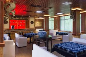 um restaurante com cadeiras brancas e um bar com luzes vermelhas em Xingping Li River Lodge em Yangshuo