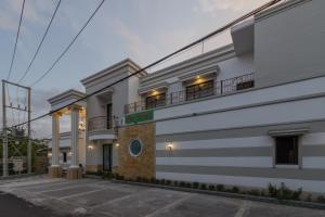 un edificio blanco con un balcón en el lateral en RedDoorz Plus near Pantai Malalayang Manado en Manado
