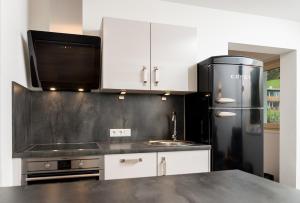 La cuisine est équipée de placards blancs et d'un réfrigérateur noir. dans l'établissement Gasthof Hubertus, à Saalfelden