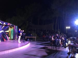 a woman standing on a stage in front of a crowd at Riva dei Greci Camping Village in Metaponto