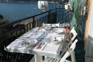 einen Tisch mit Tellern und Küchenutensilien auf dem Balkon in der Unterkunft Un gioiello con vista mare in Moneglia