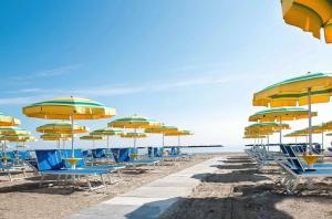 una fila di sedie e ombrelloni in spiaggia di Piccolo Hotel a Cesenatico