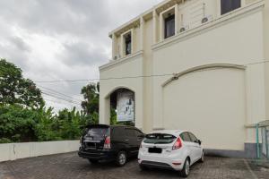 two cars parked in front of a building at RedDoorz @ Malalayang 2 Manado in Manado