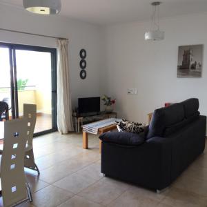 a living room with a black couch and a table at Quinta das Palmeiras in Lagos