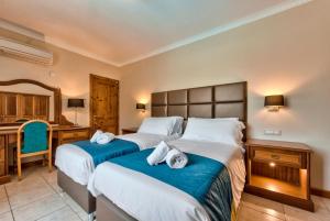 a hotel room with two beds and a desk at Baldacchino Holiday Villas in Mellieħa +37 photos