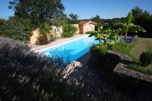 a swimming pool in a garden with a house in the background at Petite maison Peyrot in Loubejac