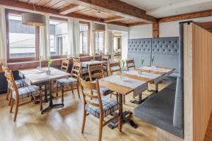 un restaurante con mesas y sillas de madera y ventanas en Hotel Daneu, en Nüziders