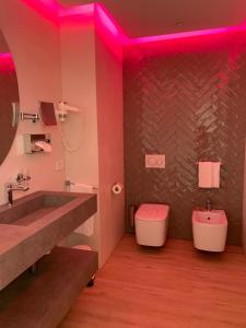 een badkamer met een wastafel, een toilet en roze verlichting bij Hotel Alexander in Milano Marittima