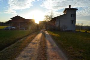 a dirt road in front of a barn with the sun setting at Agriturismo La Farazzina in Oleggio