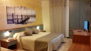 デセンツァーノ・デル・ガルダにあるAlbergo Al Cacciatoreのベッドとテレビが備わるホテルルームです。
