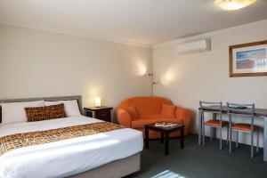 a hotel room with a bed and an orange chair at Mandarin Motel in Macksville