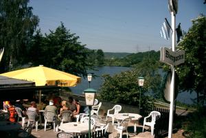 a group of tables and chairs with a view of a river at Gästezimmer auf dem Campingplatz Konz in Konz