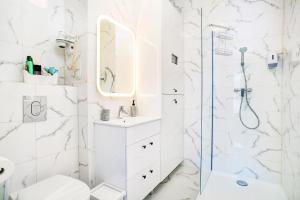 a white bathroom with a shower and a sink at Apartment Zamojska 8 - Apartamenty GKM Lublin in Lublin
