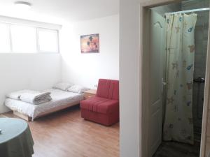 um quarto com uma cama e uma cadeira vermelha em Studio Milivojevic em Sokobanja