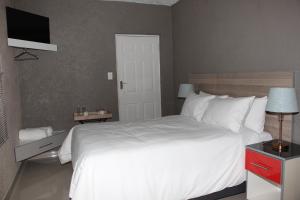 um quarto com uma cama branca e uma televisão em View Inn Exclusive Lodge em Nelspruit