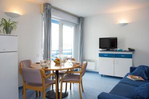 uma sala de estar com uma mesa e cadeiras e uma televisão em Hôtel & Résidence Vacances Bleues Orhoïtza em Hendaye