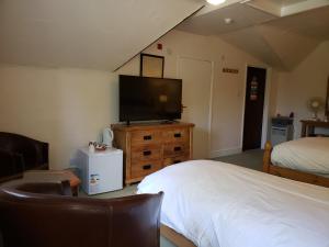 a bedroom with a bed and a flat screen tv at Clifton Hampden B&B in Clifton Hampden