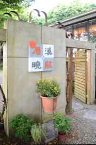 ein Schild an einer Wand mit einer Pflanze in einem Topf in der Unterkunft Nantou Puli Sunrise Villa Homestay B&B in Puli