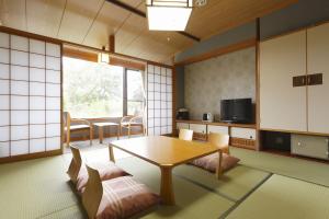 a room with a table and chairs and a kitchen at Kyukamura Noto-Chirihama in Hakui
