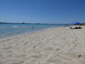 a beach with people laying on the sand and the water at HG Jardín de Menorca in Son Bou